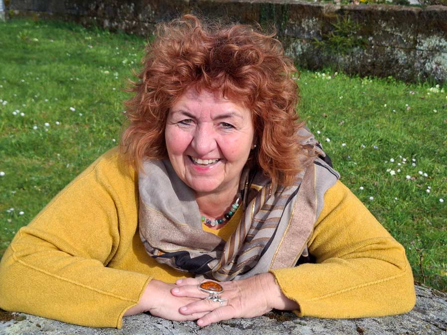 Pamela Anna Guggenheim stützt sich auf einen Fels und lächelt in die Kamera.